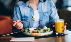 žena konzumuje jedlo, ktoré môže znížiť cholesterol